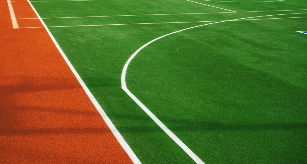 Artificial grass with markings on the sports ground for playing tennis and basketball, close-up.